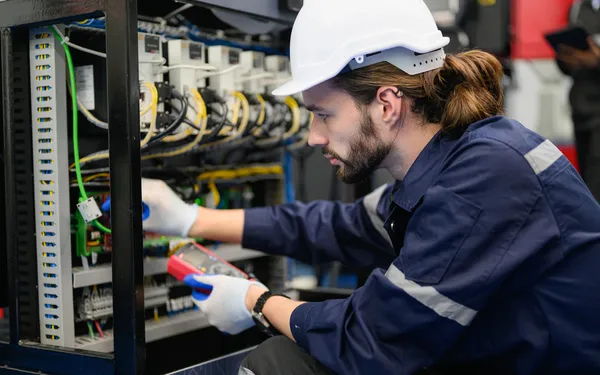 Acercamiento a un hombre profesional haciendo un mantenimiento eléctrico dentro del plantel industrial.