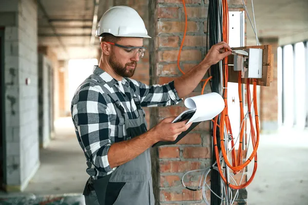 Vista general de un experto con el equipo adecuado dentro de una instalación realizando un dictamen de verificación de instalaciones eléctricas.