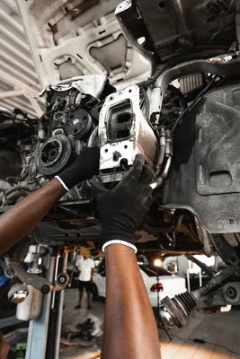 Manos de mecánico trabajando en la estructura del motor de un vehículo durante un retrofit eléctrico en México.