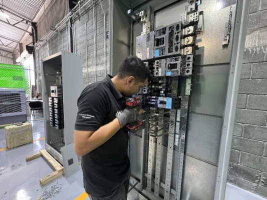 Técnico calificado utiliza herramientas para la modernización y el retrofit de componentes internos en un tablero industrial.